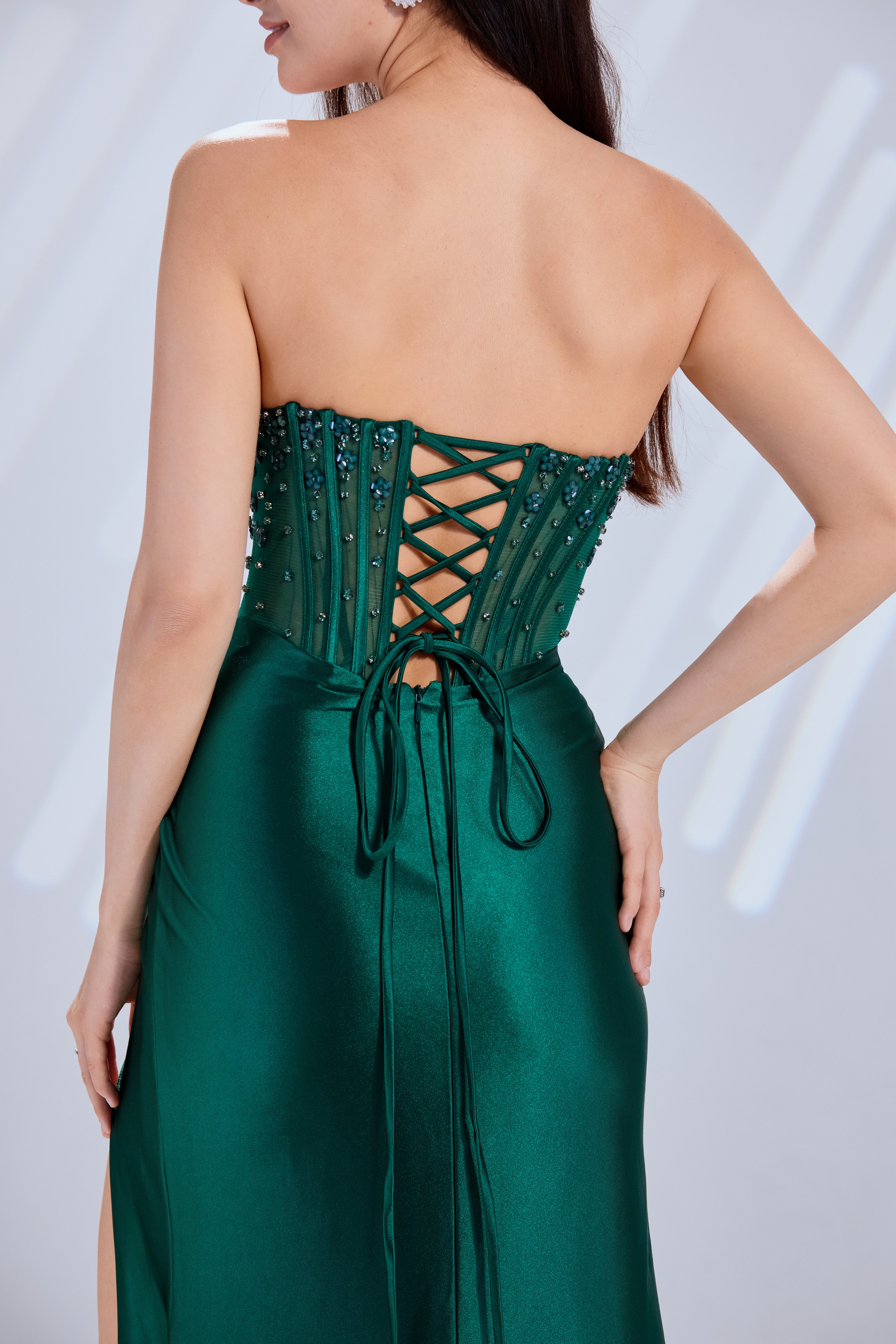 Emerald green corset bodice with crisscross lacing and tie detail, long draped skirt