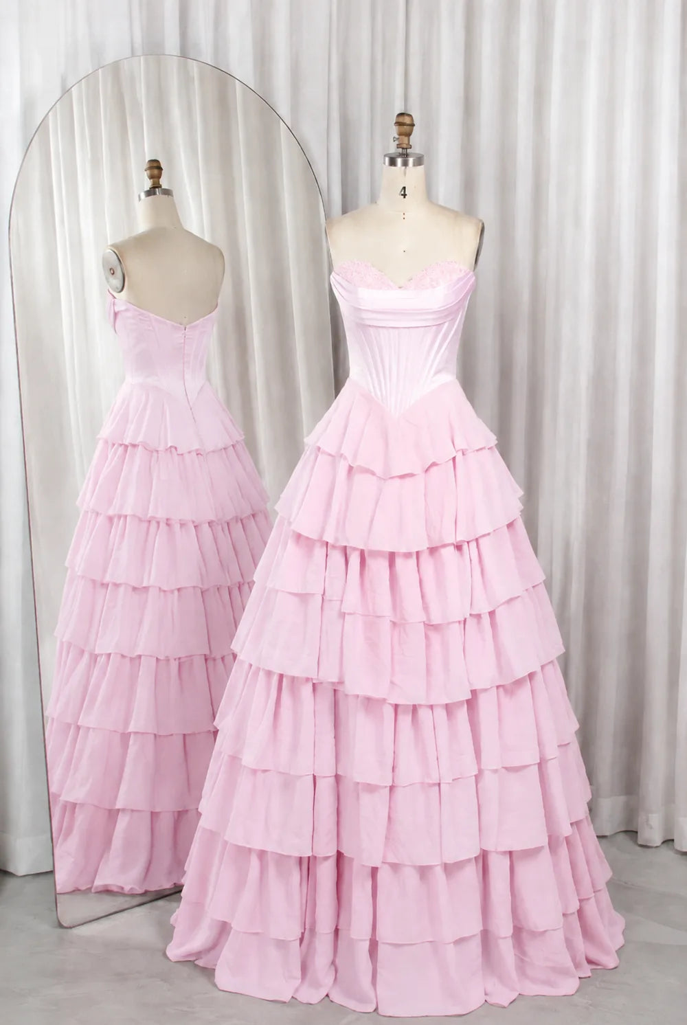 Pink strapless tiered ruffle ball gown with corset-style bodice, fitted waist.