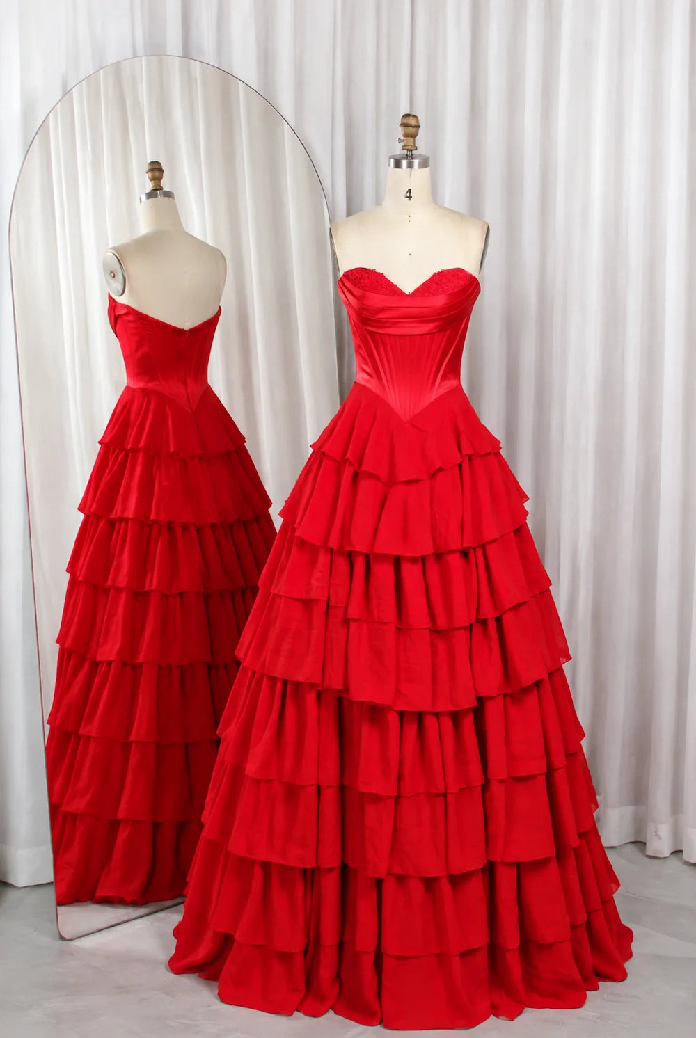 Red tiered ruffle prom ball gown on mannequins, corset bodice, tiered skirt