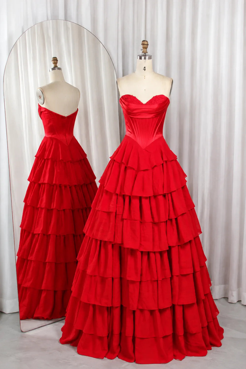 Red tiered ruffle prom ball gown on mannequins, corset bodice, tiered skirt