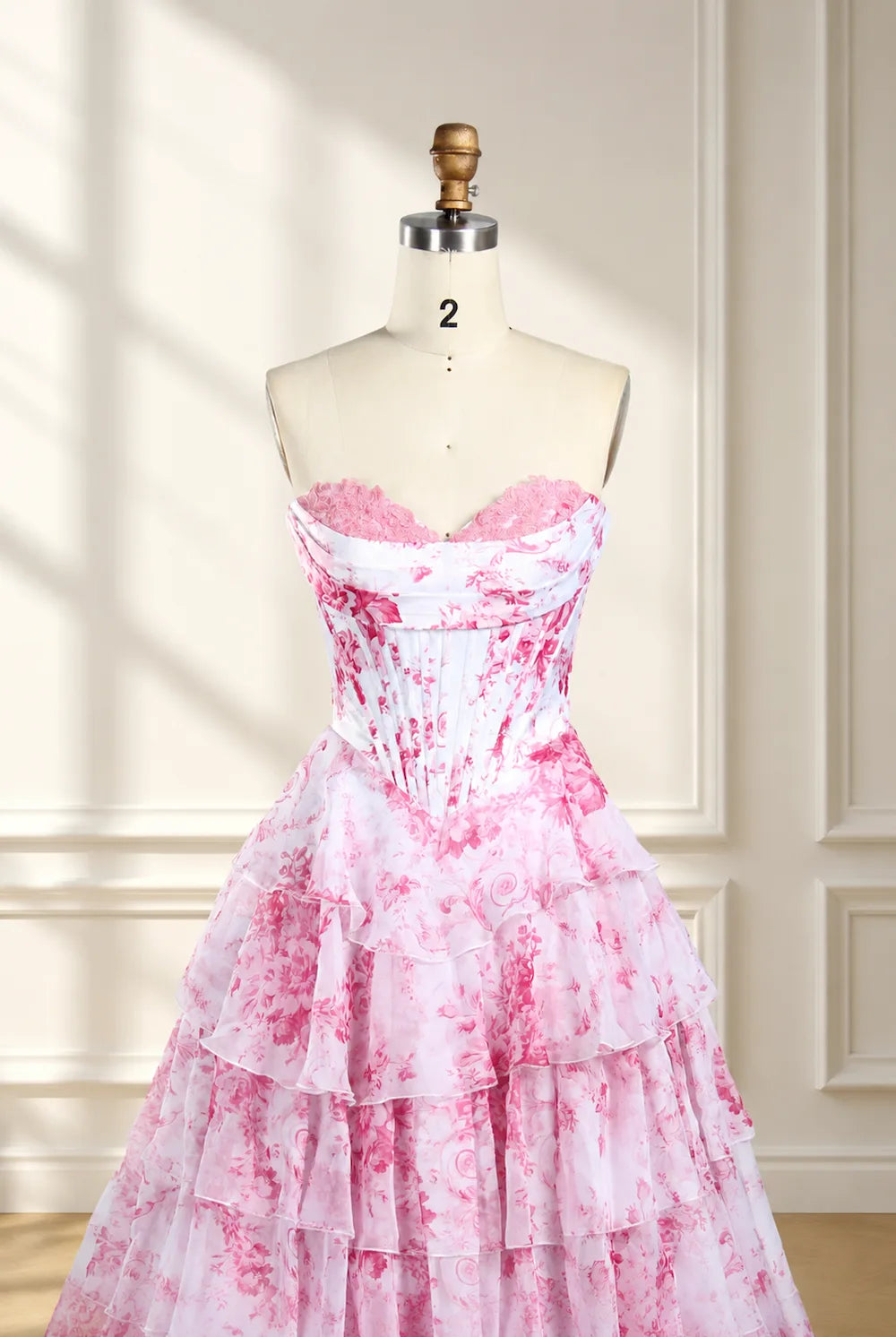 Pink-and-white floral print corset ball gown on mannequin, strapless sweetheart ruffles