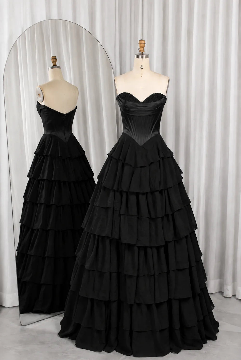 Black strapless corset-style bodice ball gown with tiered ruffle layers.