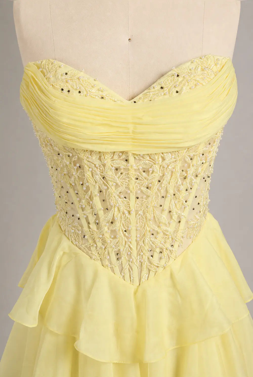 Yellow sweetheart corset-style tulle gown with beaded texture and layered ruffle skirt