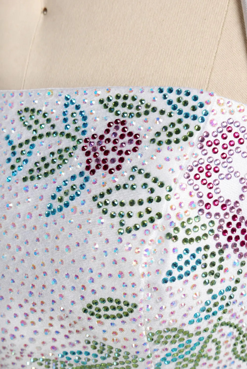 Close-up of white sequin fabric with multicolor rhinestone floral pattern