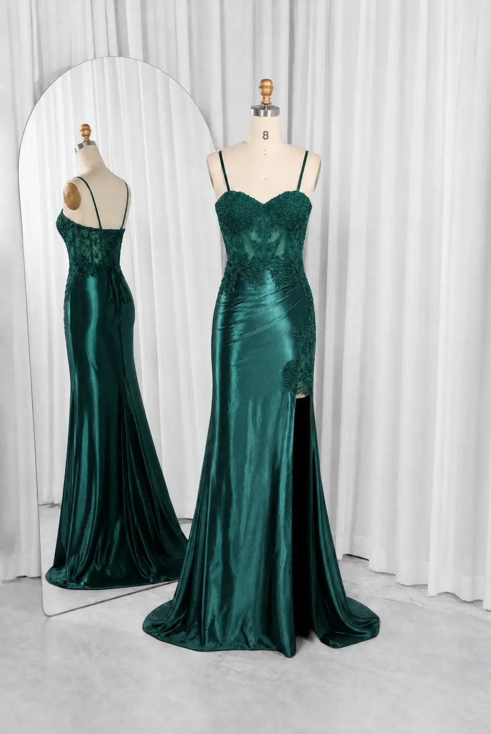 Emerald green satin evening gown on mannequin, lace corset with thin spaghetti straps