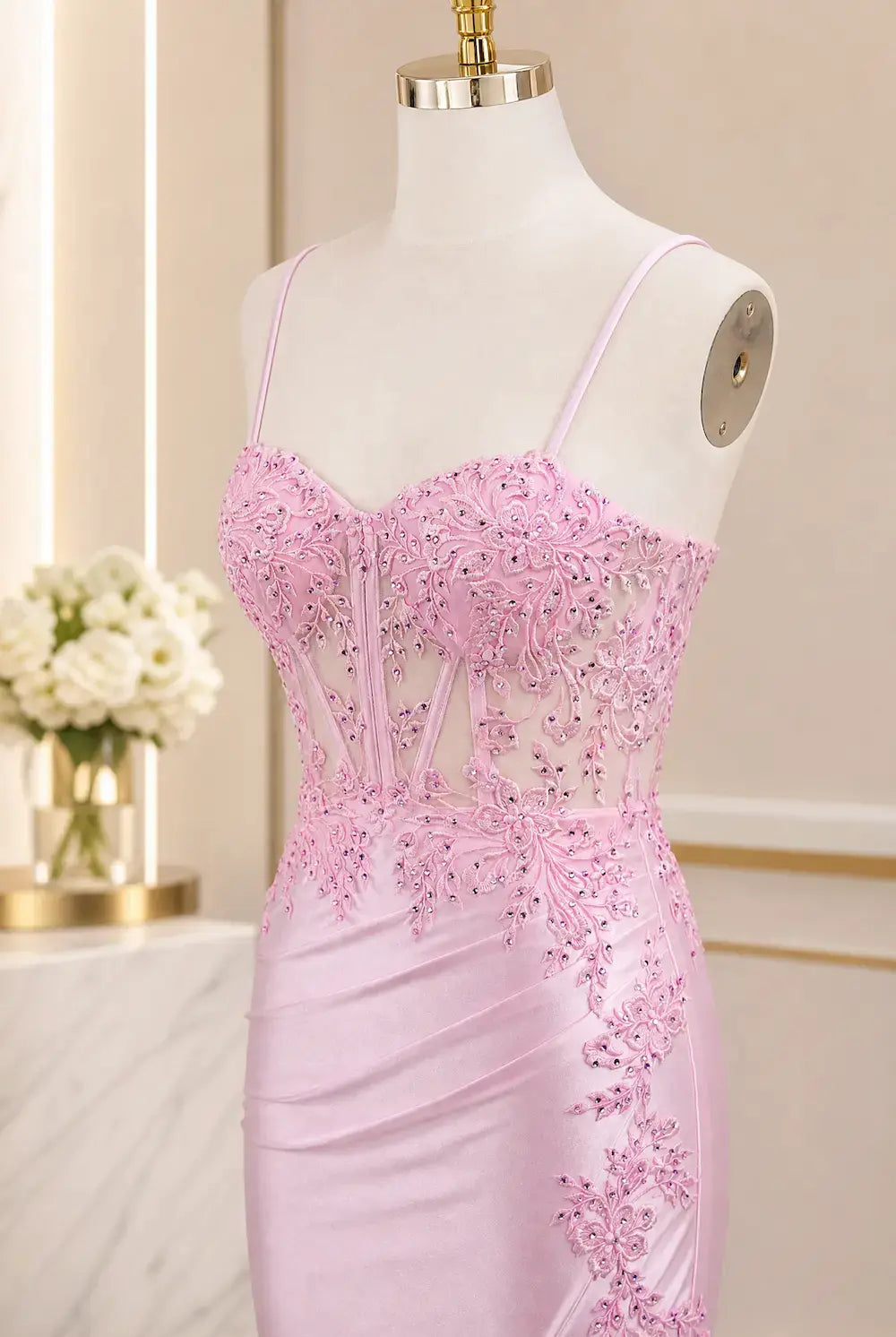 Pink corset evening dress on mannequin with spaghetti straps and beadwork