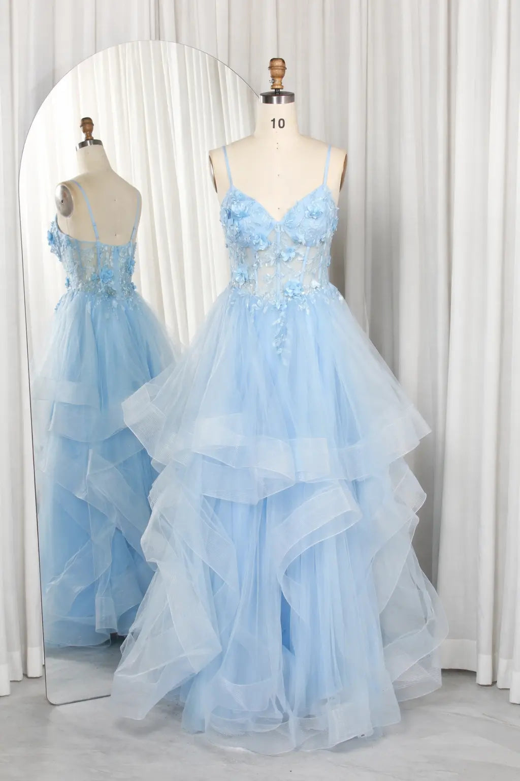 Blue spaghetti-strap tiered tulle prom dress on mannequin, 3D floral details