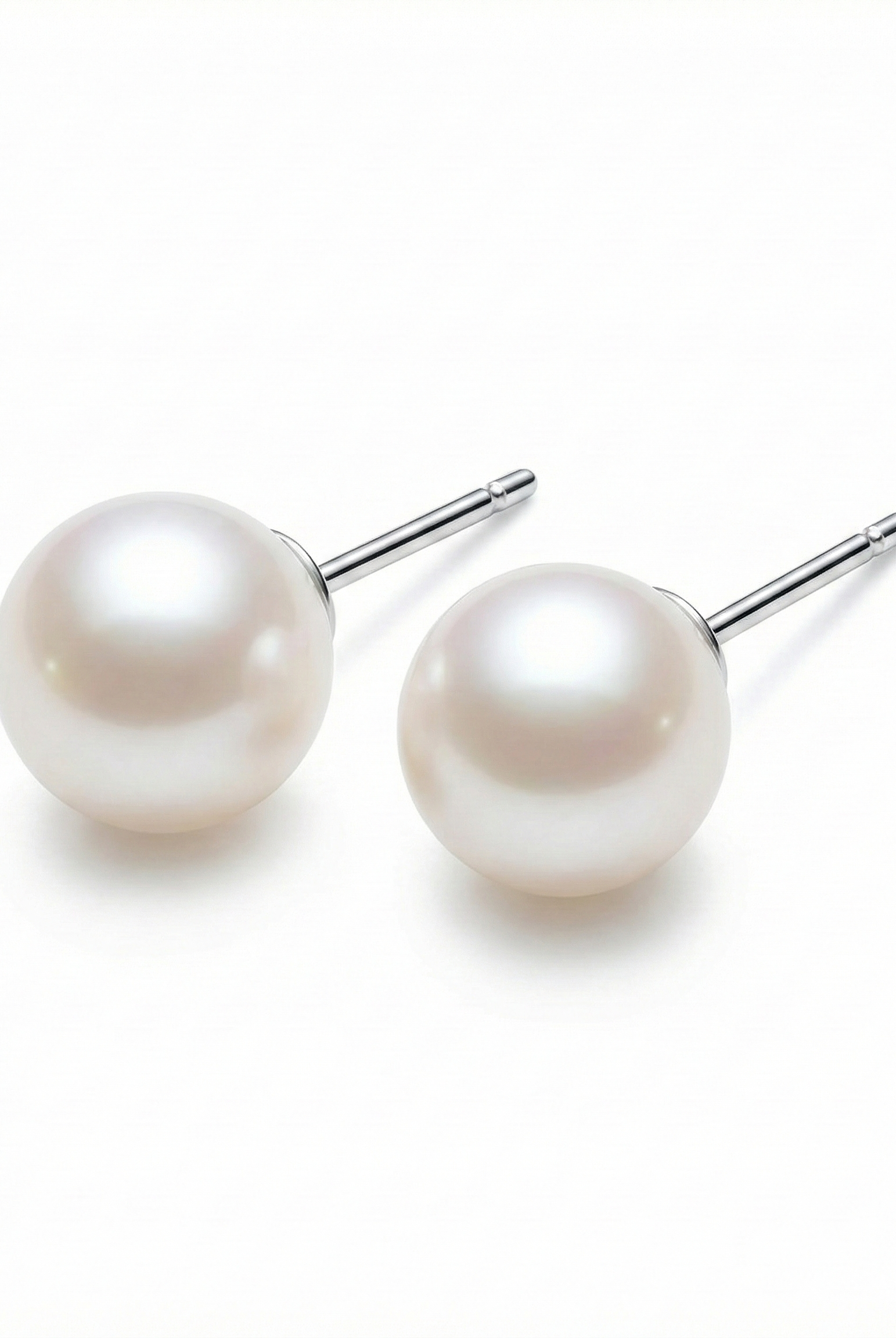 Round white pearl stud earrings with thin silver posts, minimalist pair