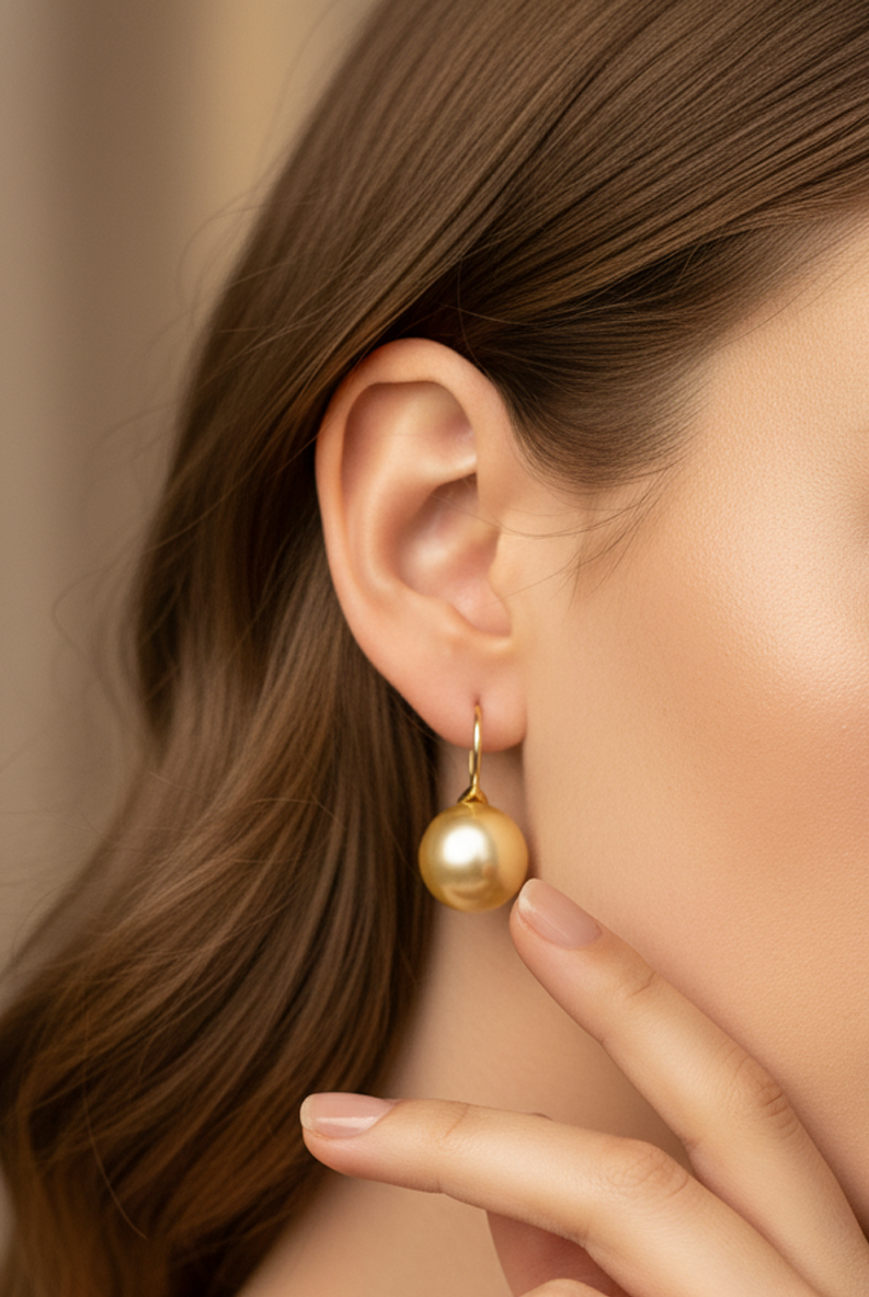 Gold round pearl drop earrings on ear with thin French hooks