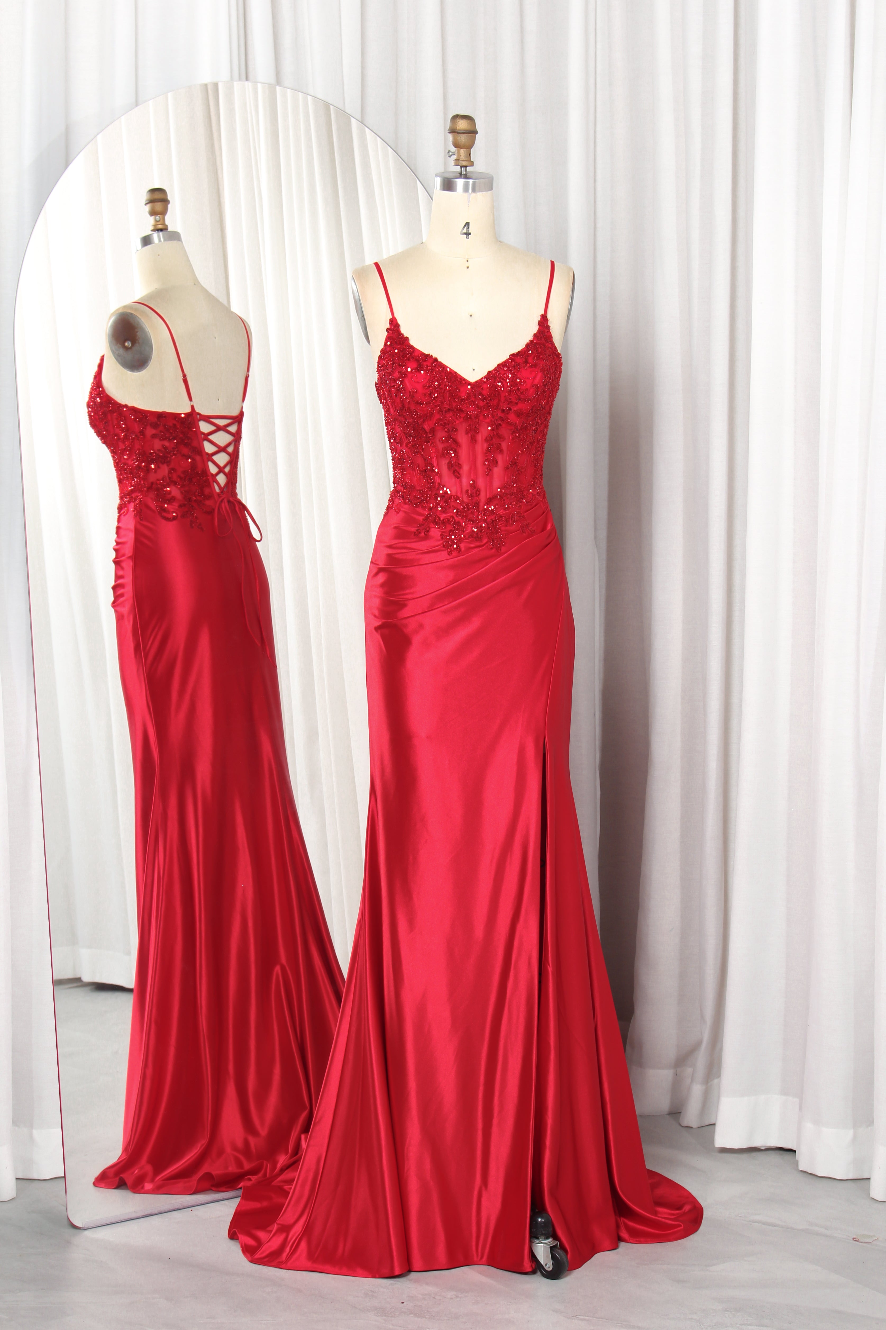 Front and back view of a navy blue evening gown featuring a sequined lace corset bodice with spaghetti straps and a draped satin skirt with a high slit.