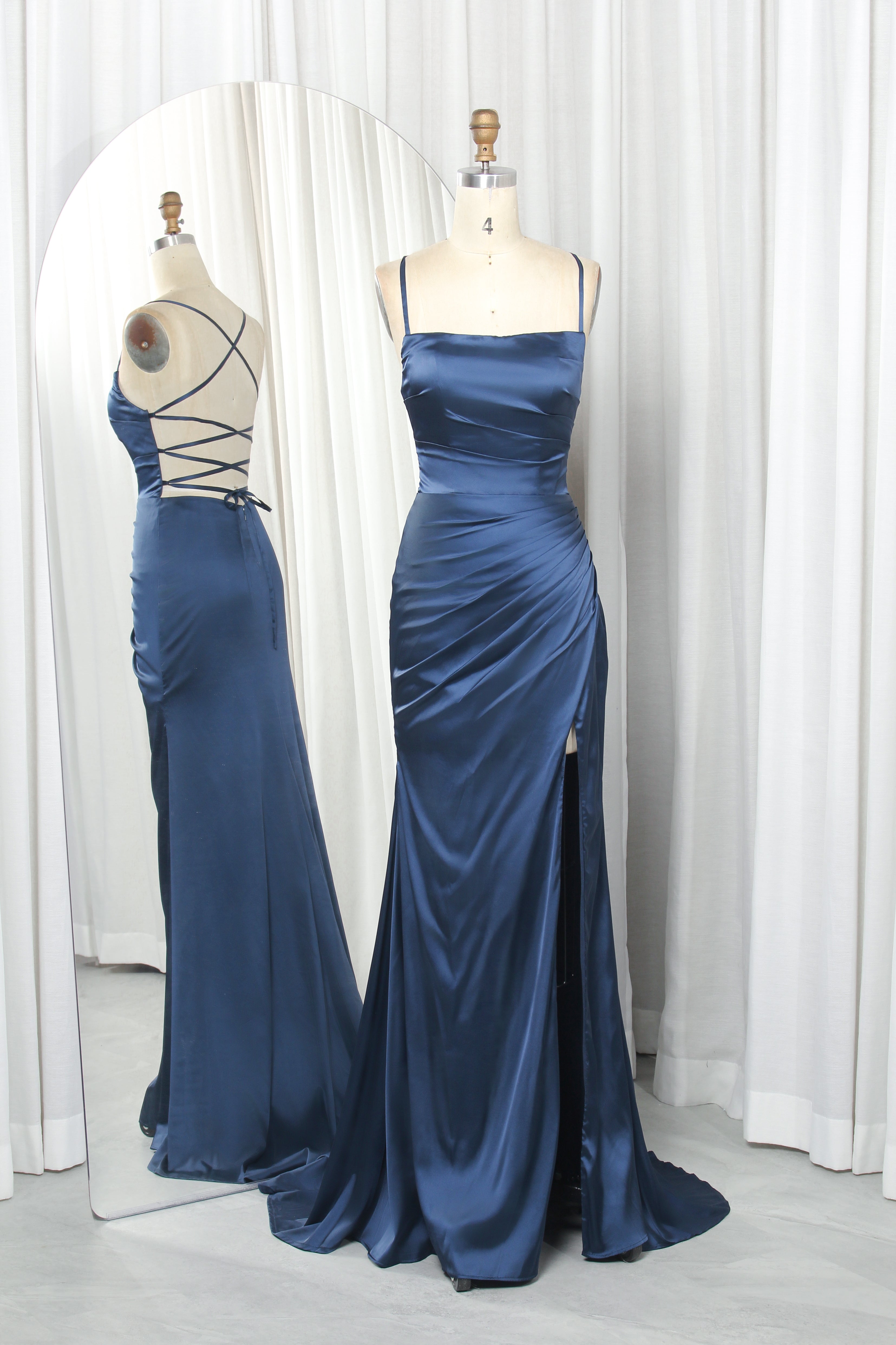 Fitted dark blue satin spaghetti strap formal dress with criss-cross back straps and leg slit.