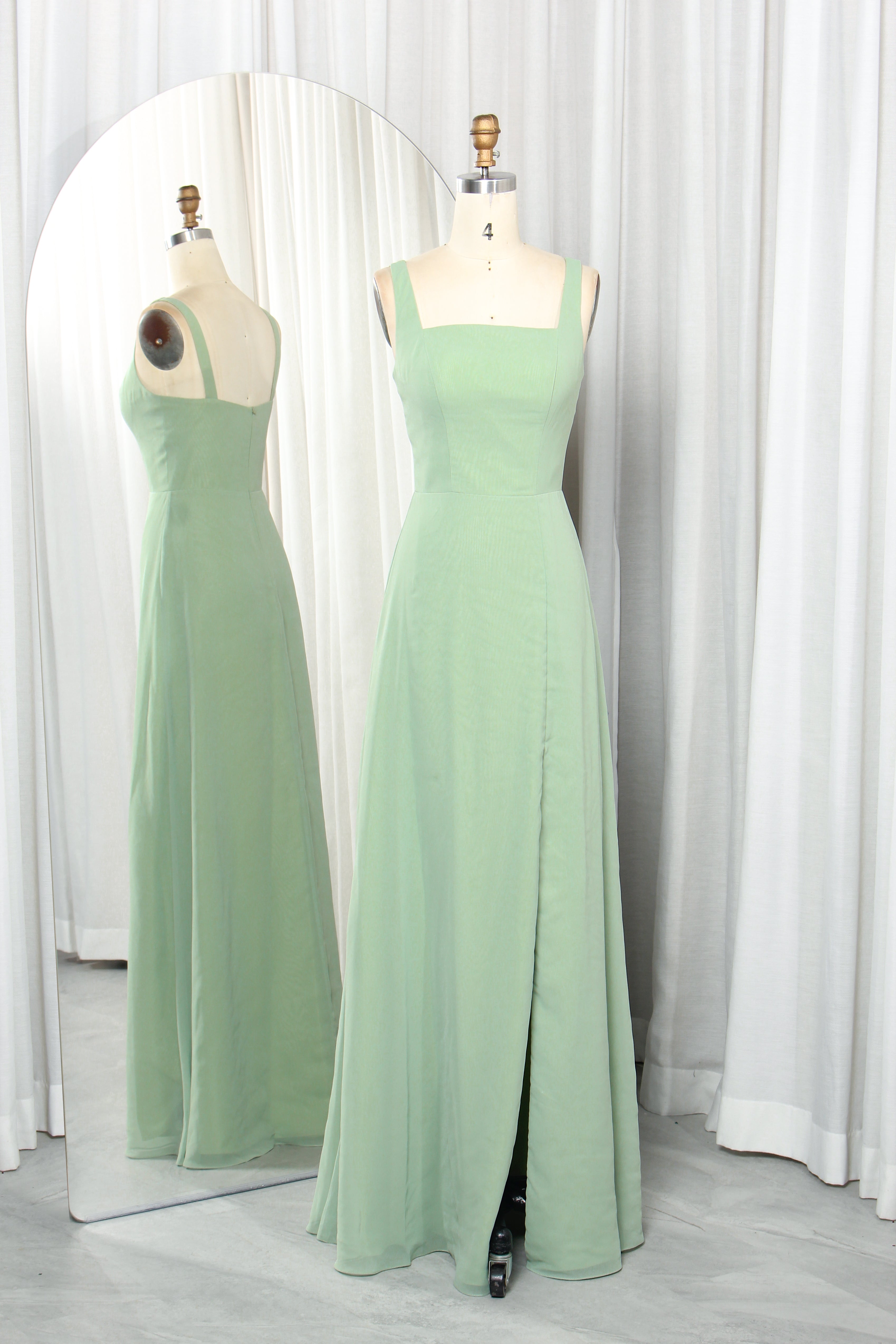 Sage green square-neck chiffon slit gown with sleeveless fitted bodice on mannequins