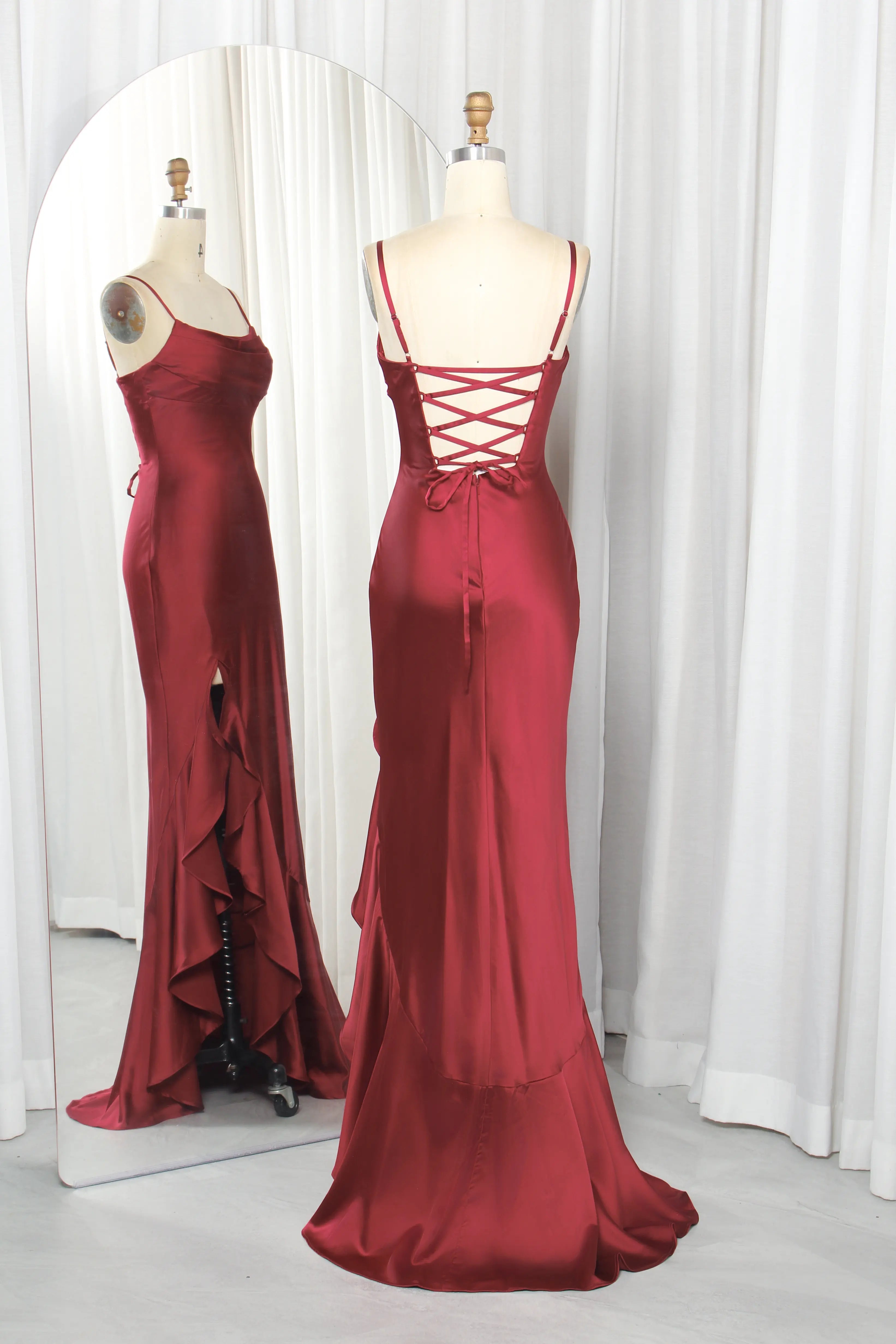 Wine satin prom gown on mannequin, with crisscross lace-up back and ruffled thigh slit.