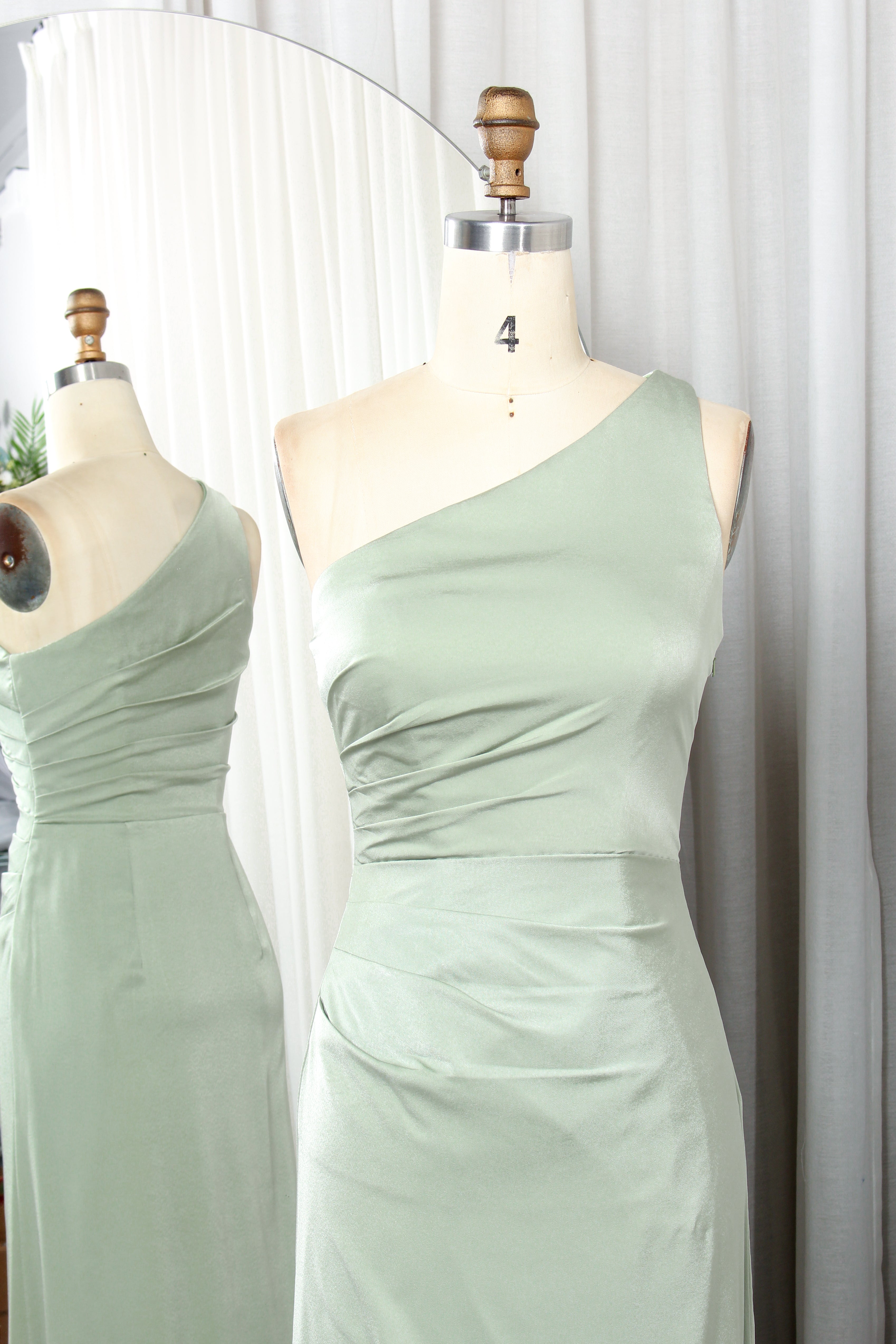 Light green one-shoulder dress with a high slit displayed on a mannequin.