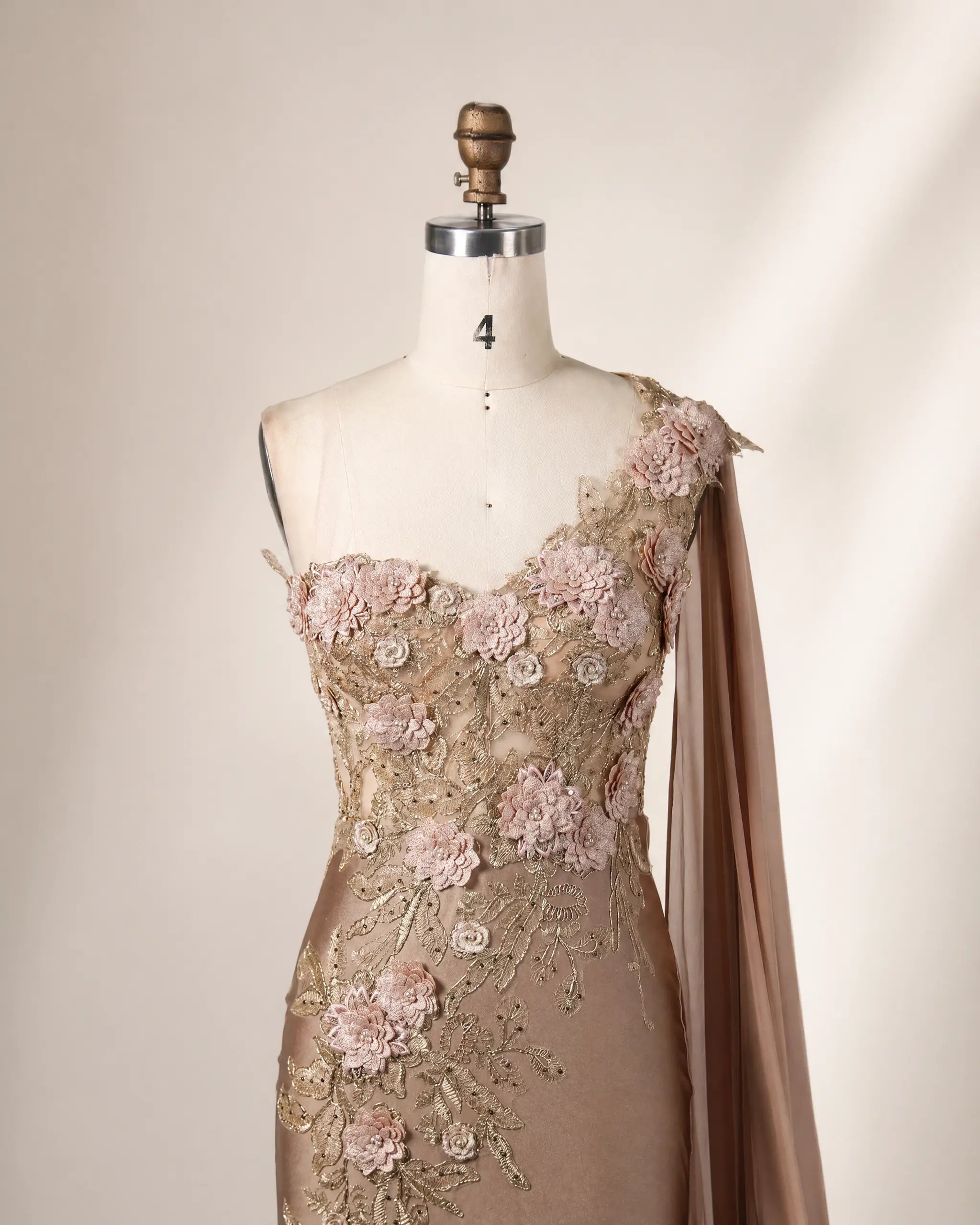 Champagne one-shoulder satin gown with detailed 3D floral appliqués and draped sleeve