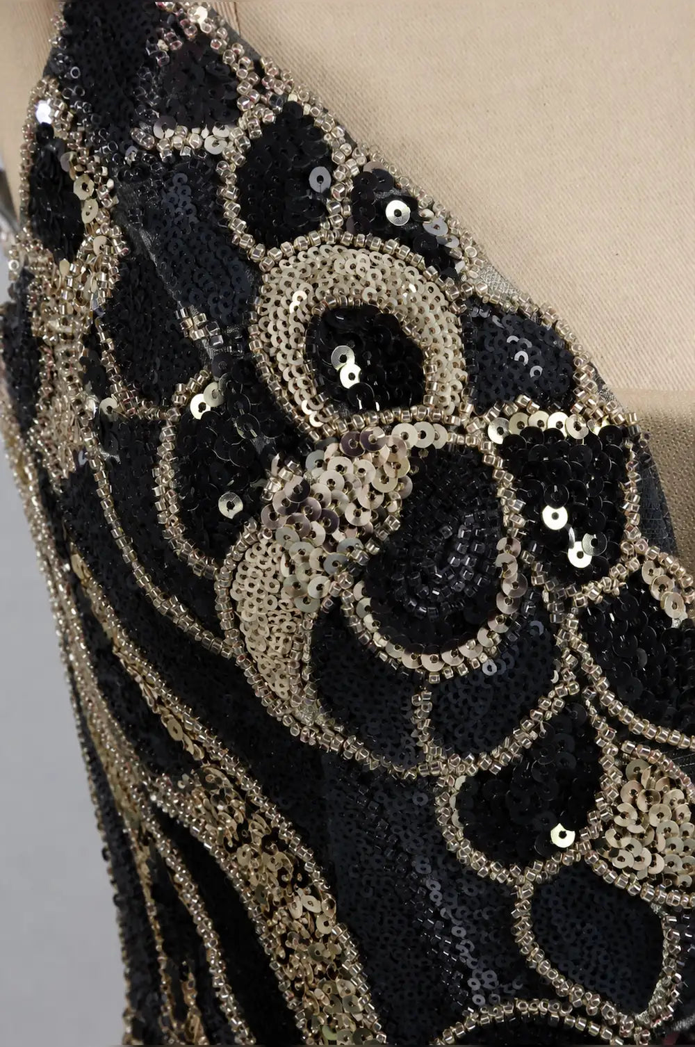 Black and gold sequin mini dress with ornate swirl and bead details, close-up