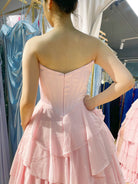 Structured corset tiered ruffle ball gown in light pink, open-back style and tiered skirt.