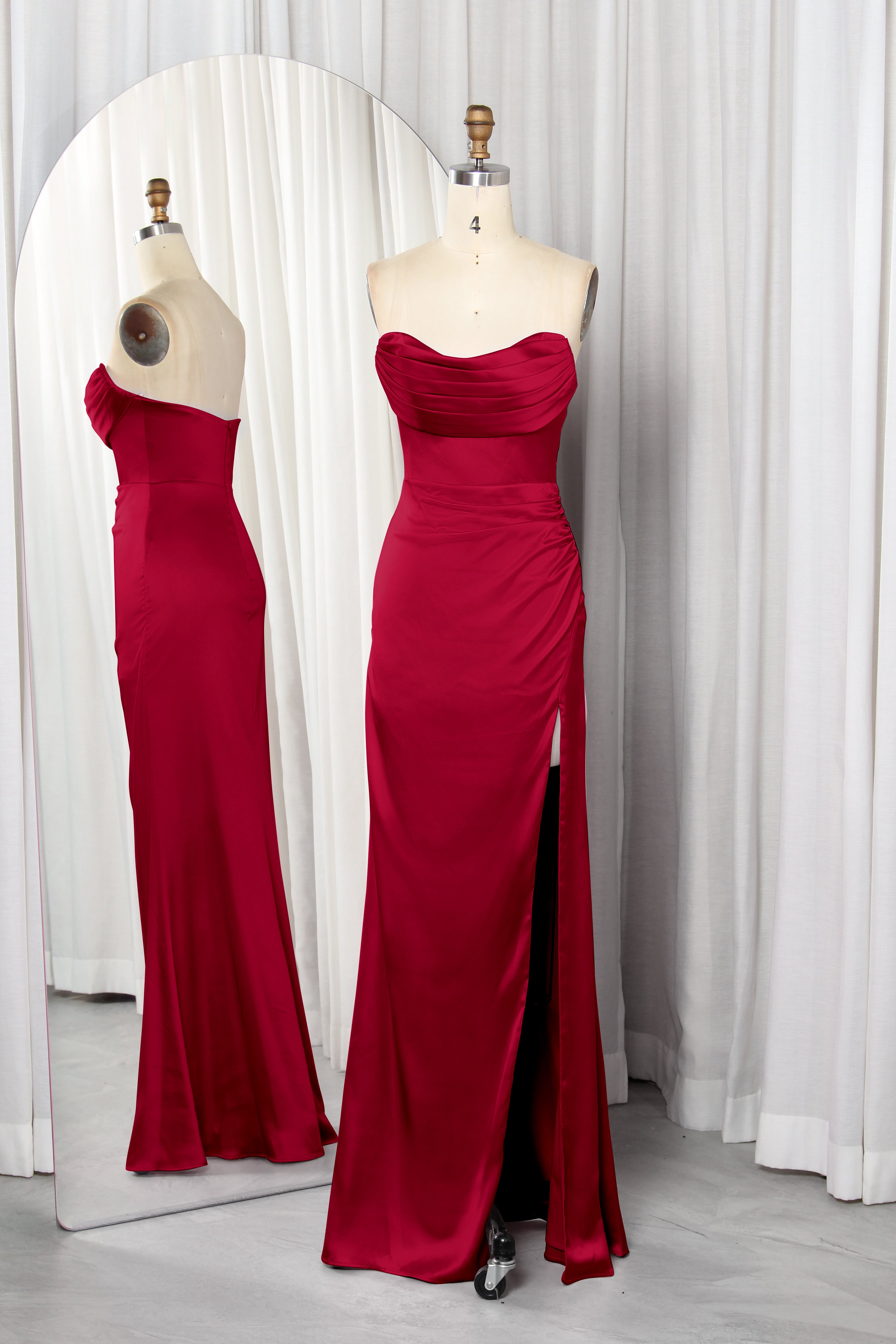 Front and back view of a vibrant red strapless satin evening gown with a ruched sweetheart neckline and high leg slit on a mannequin.