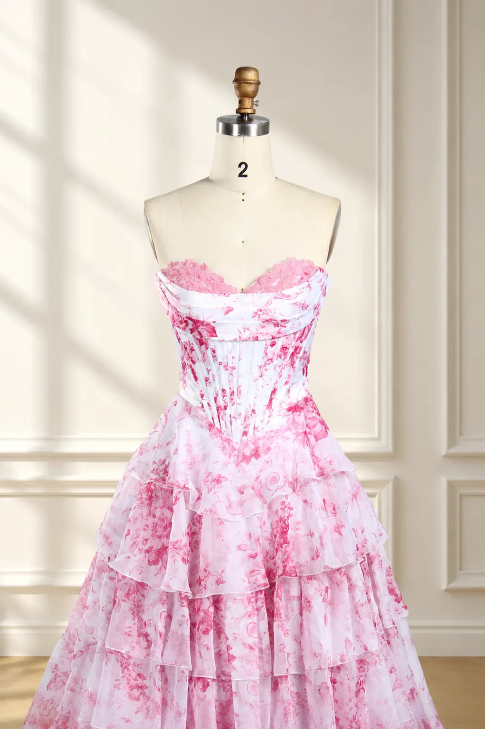 Pink-and-white floral print corset ball gown on mannequin, strapless sweetheart ruffles