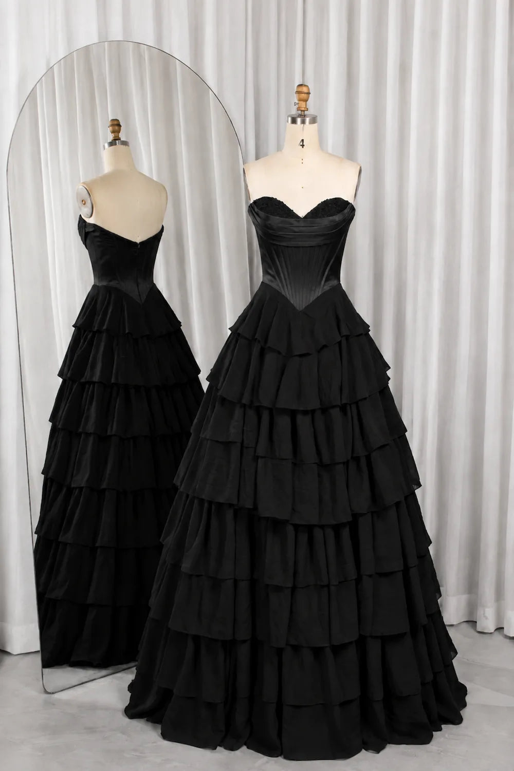 Black strapless corset-style bodice ball gown with tiered ruffle layers.