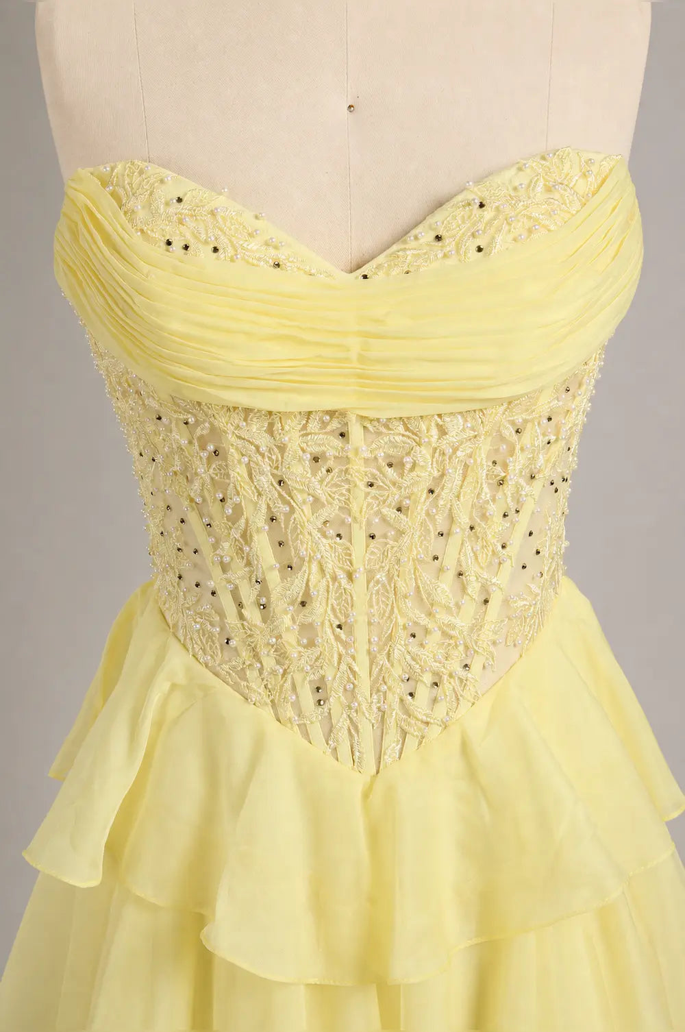 Yellow sweetheart corset-style tulle gown with beaded texture and layered ruffle skirt