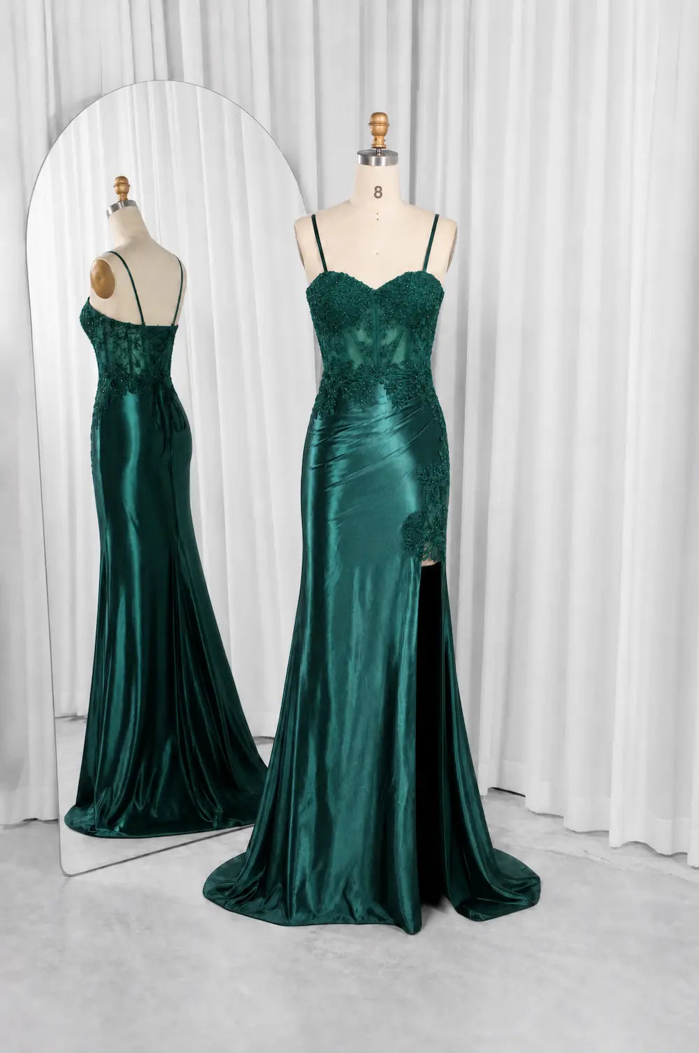 Emerald green satin evening gown on mannequin, lace corset with thin spaghetti straps