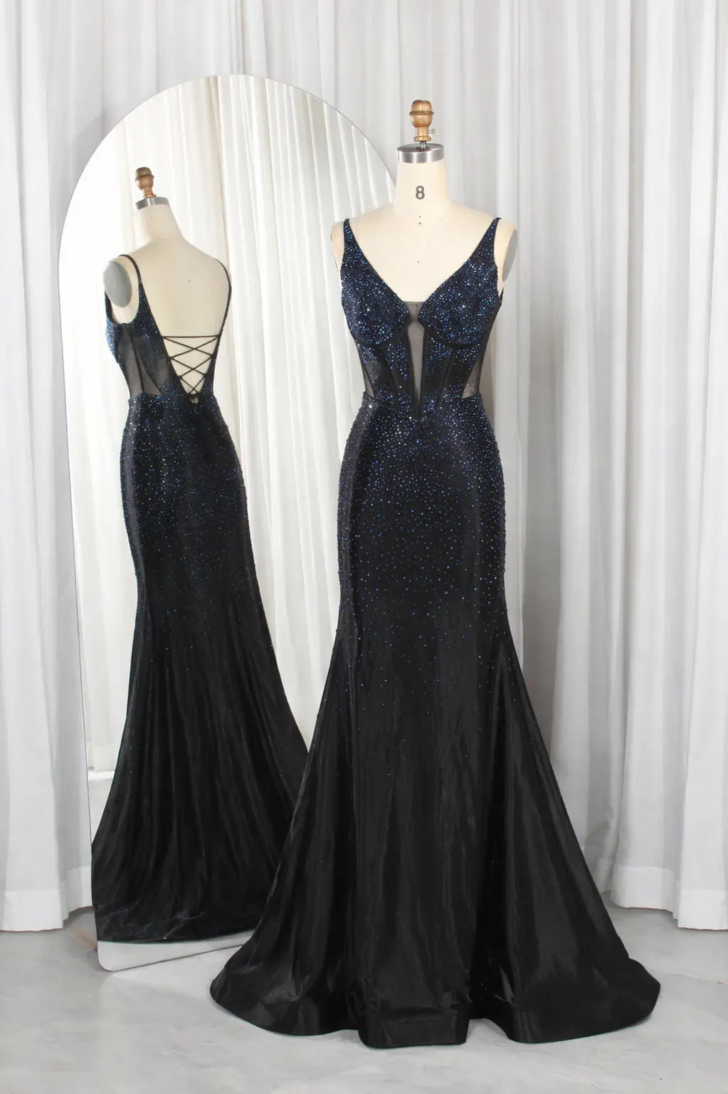 Navy rhinestone corset mermaid prom dress with open back and crisscross straps.