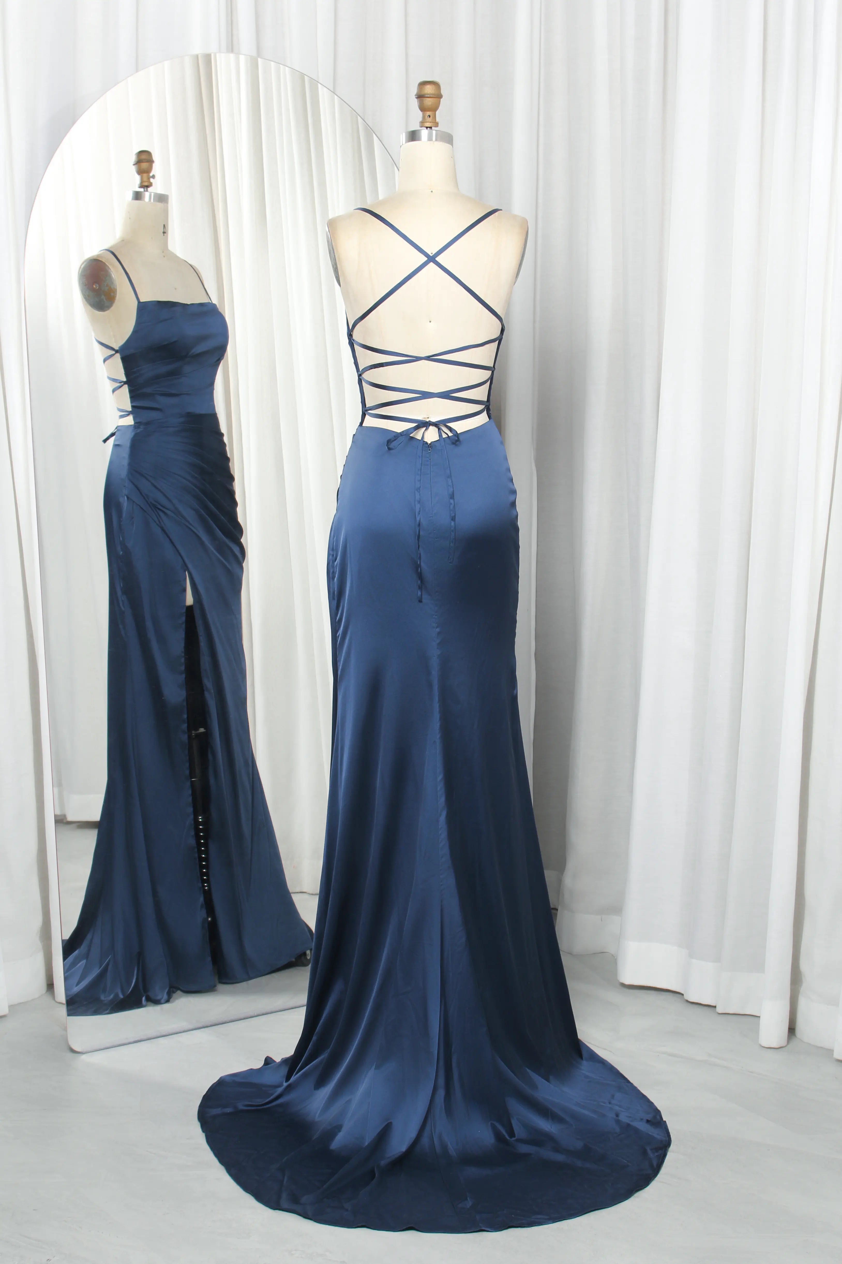 Navy satin prom gown on mannequins with criss-cross lace-up back and slit skirt