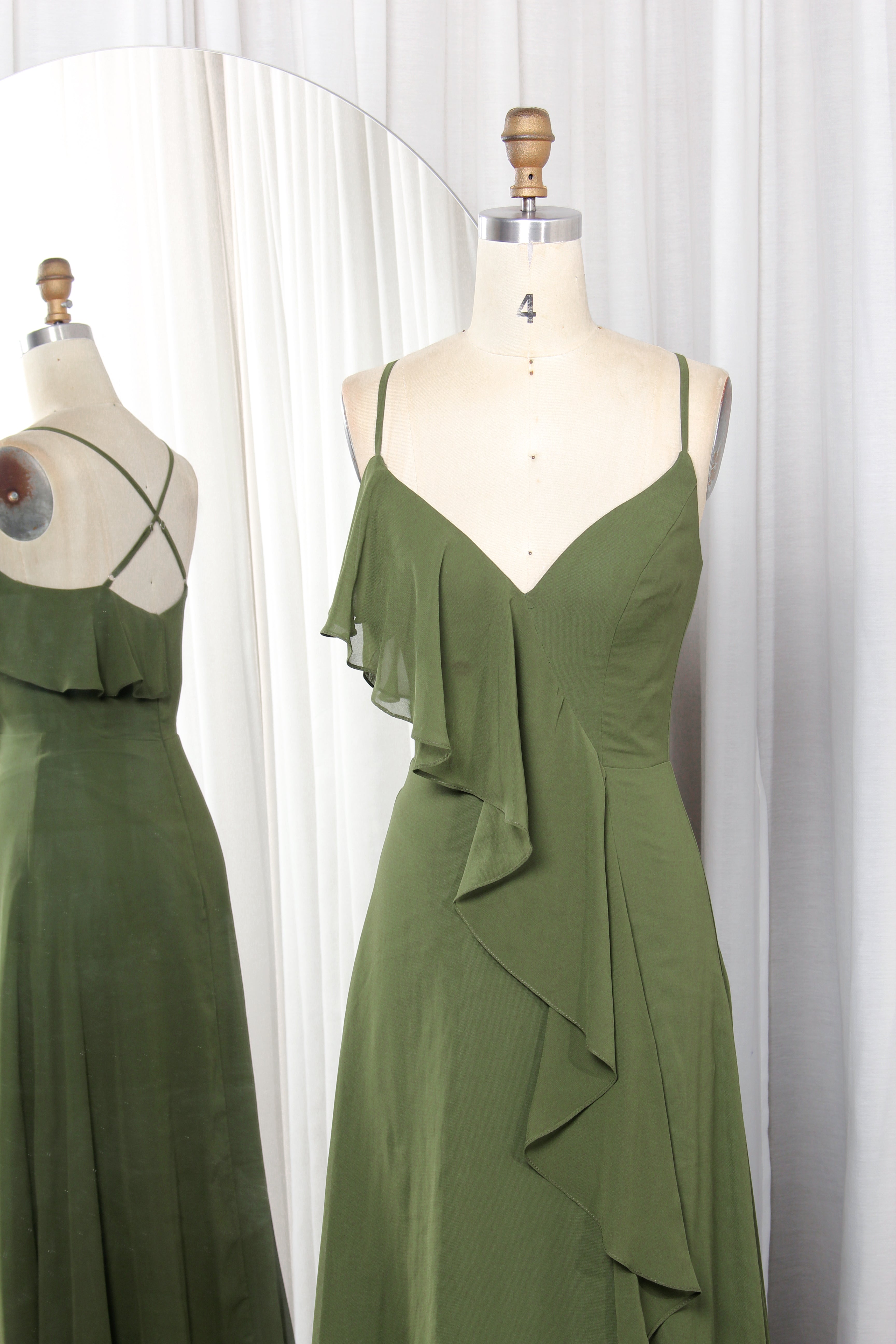 Olive green chiffon bridesmaid dress with spaghetti straps, V-neckline, and cascading ruffles on a mannequin