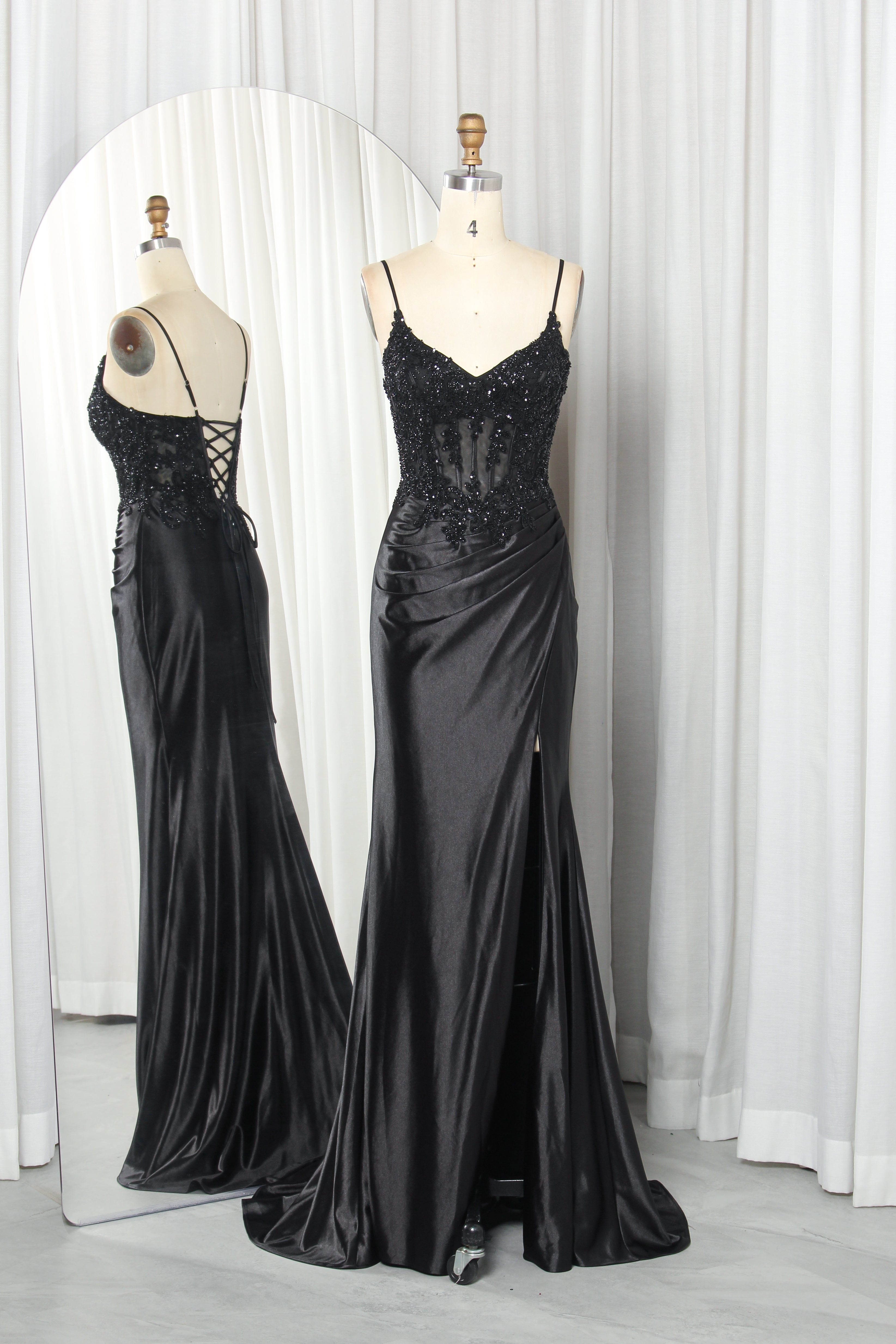 Front and back view of a navy blue evening gown featuring a sequined lace corset bodice with spaghetti straps and a draped satin skirt with a high slit.