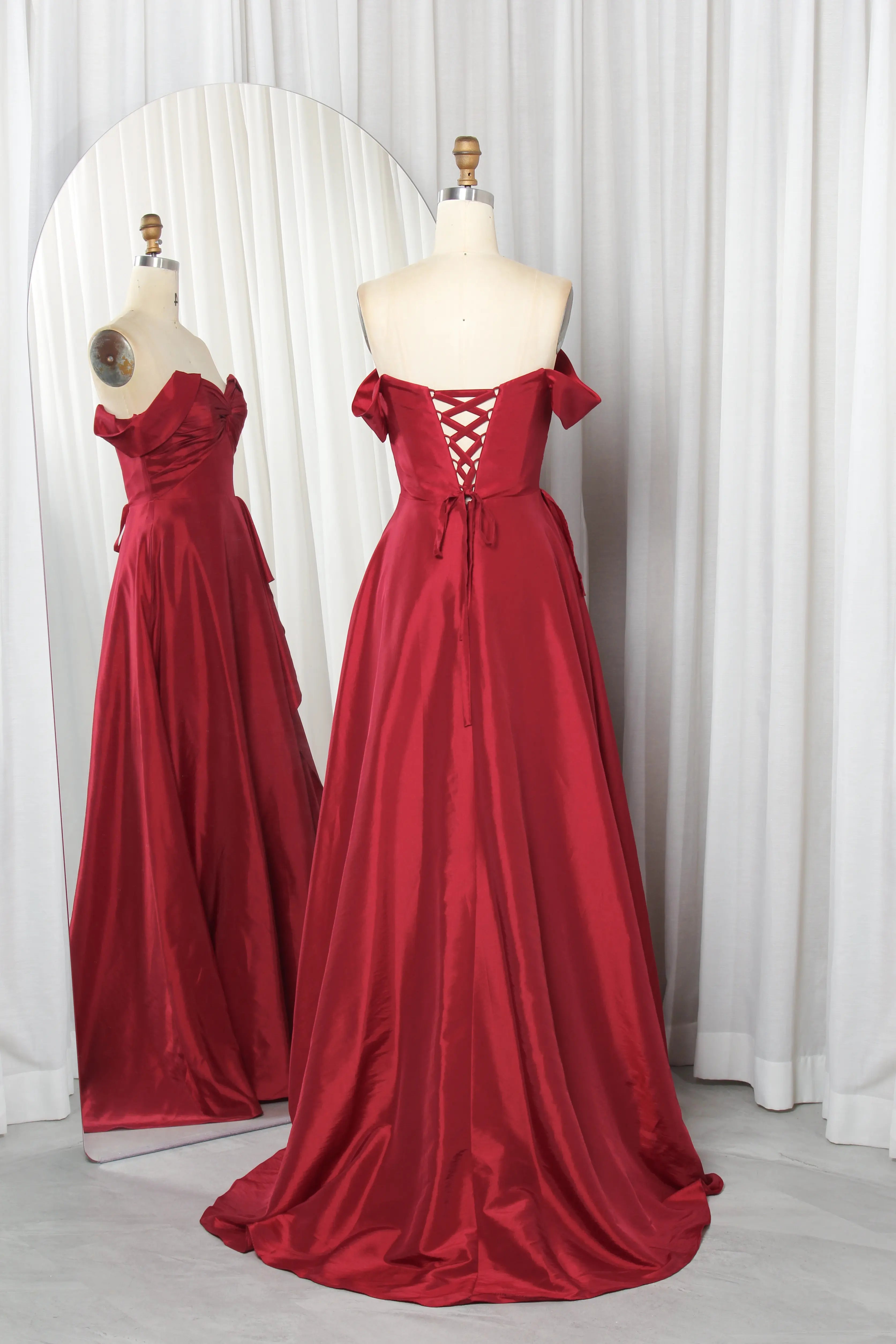Wine off-shoulder prom gown on dress forms, corset back with crisscross lacing