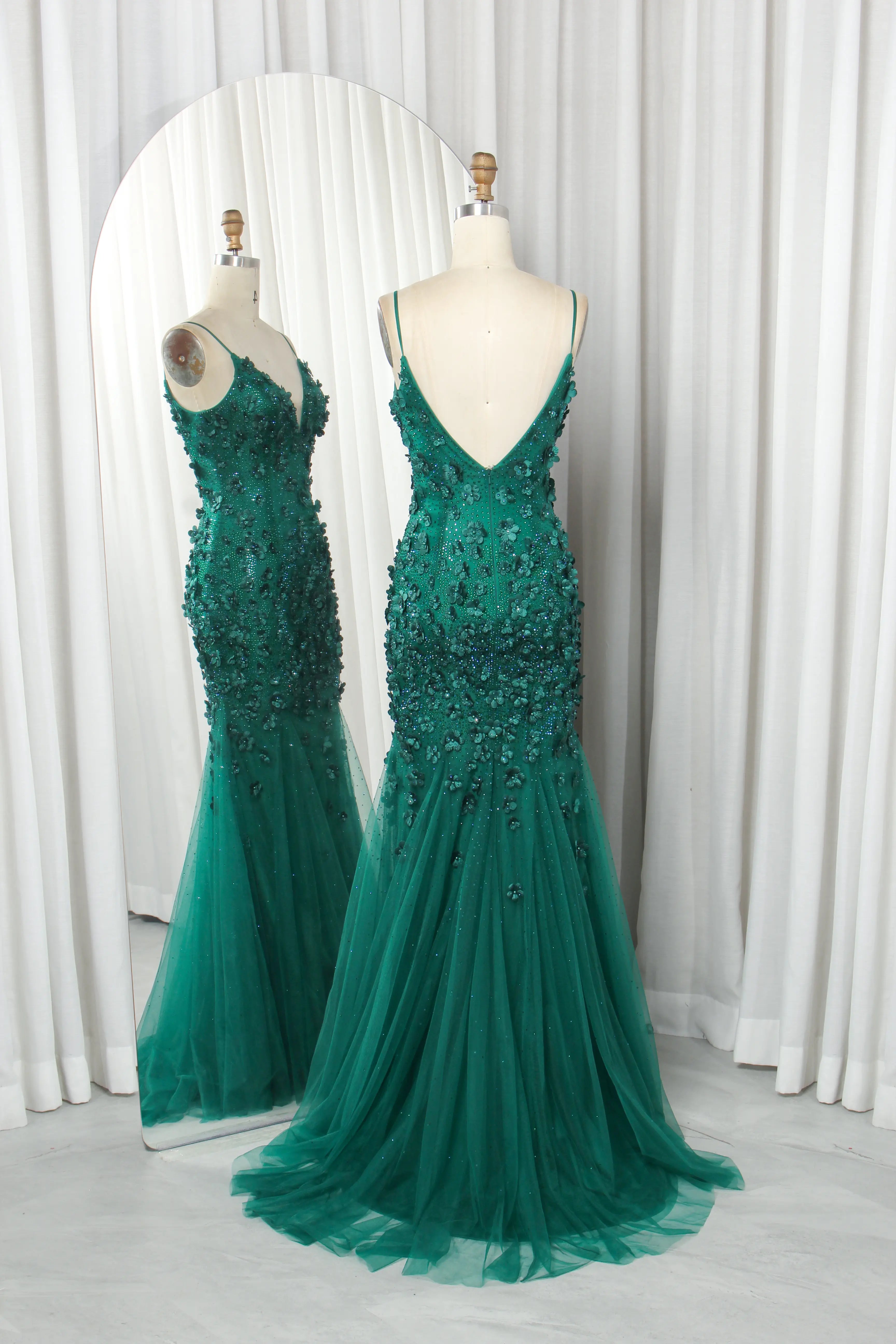 Emerald green sequined mermaid prom dress on mannequins, V-neck and low V-back