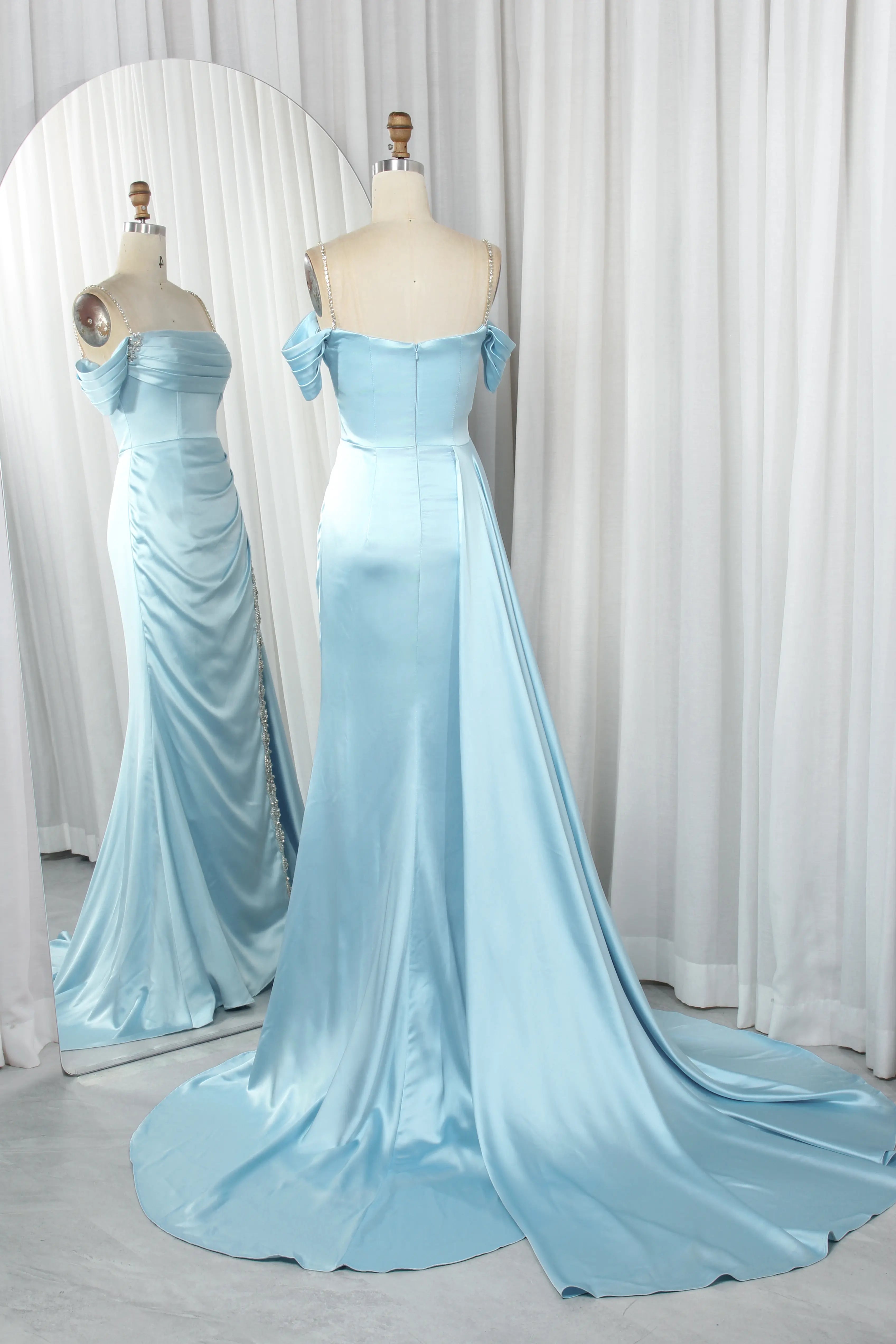 Light blue satin prom dress on mannequin, off-shoulder neckline, crystal trim panel, long drape
